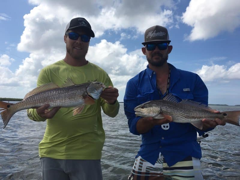 Inshore Fishing Trips - guests holding redfish on the water