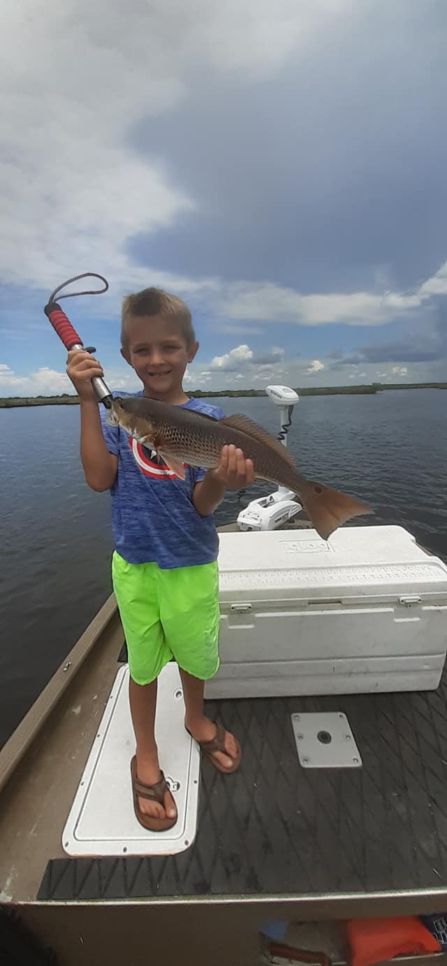 boy holding redfish with grippers
